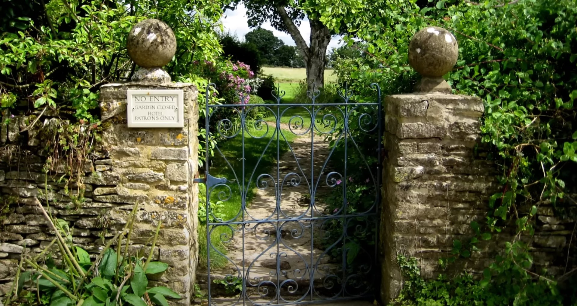 Landscape Architecture and Design - Portsmouth Landscaping Elegant garden entrance with stone pillars, ornate iron gate surrounded by lush greenery and professional landscaping
